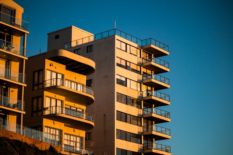 Modern apartment buildings with unique facades illuminated by sunset lighting.